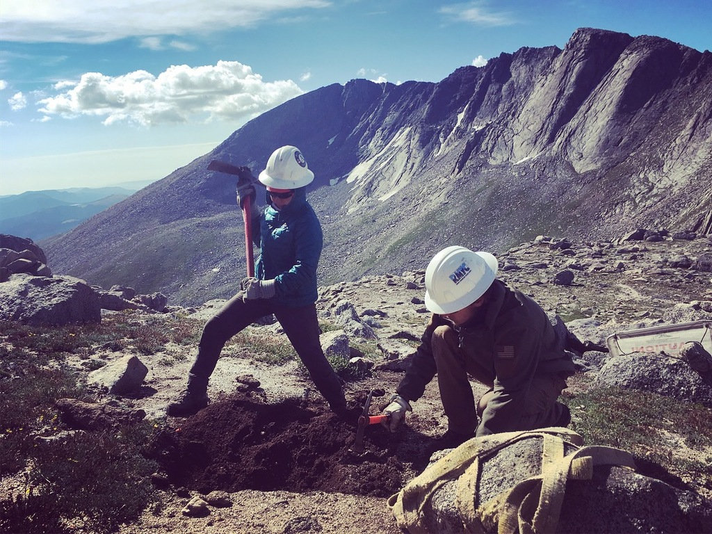 Land Acknowledgement: two trail workers dig into a mountainous path.